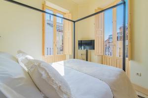 a bedroom with a bed and two windows at Mosaiko Homes Catedral Granada in Granada