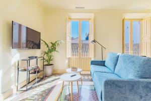 a living room with a blue couch and a tv at Mosaiko Homes Catedral Granada in Granada