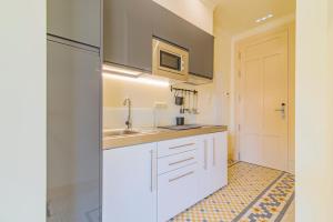a kitchen with white cabinets and a sink at Mosaiko Homes Catedral Granada in Granada