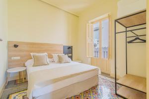 a bedroom with a large white bed and a window at Mosaiko Homes Catedral Granada in Granada