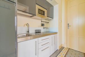 a small kitchen with white cabinets and a sink at Mosaiko Homes Catedral Granada in Granada