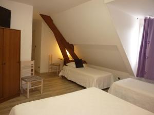 a attic bedroom with two beds and a window at Hôtel A La Renommée in Saint-Père