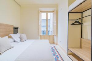 a bedroom with a large white bed and a window at Mosaiko Homes Catedral Granada in Granada