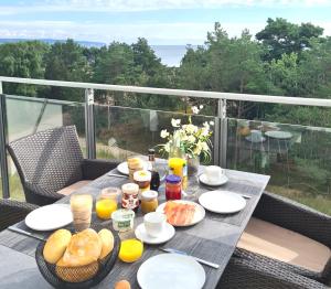 een tafel met ontbijtproducten en drankjes op een balkon bij Loftappartement Sundowner mit fantastischem Meerblick in Prora in Binz