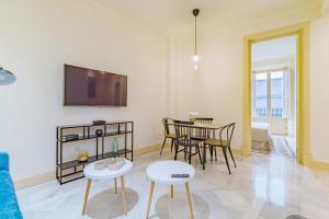 a living room with a table and chairs and a tv at Mosaiko Homes Catedral Granada in Granada