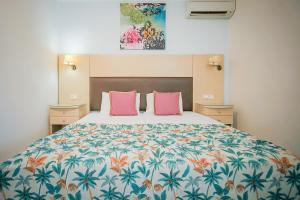 ein Schlafzimmer mit einem großen Bett mit rosa Kissen in der Unterkunft Rose Club Apartments in Laganas