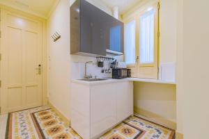 a kitchen with white cabinets and a sink and a window at Mosaiko Homes Catedral Granada in Granada