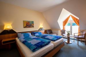 ein Schlafzimmer mit einem Bett mit blauer Decke und einem Fenster in der Unterkunft Hotel Brückenschänke in Sebnitz