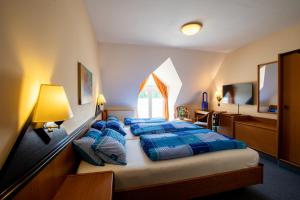 a bedroom with two beds with blue comforters and a window at Hotel Brückenschänke in Sebnitz