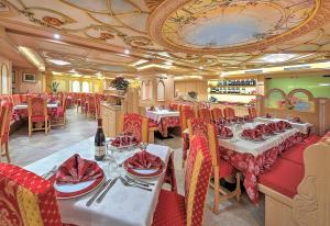フォルガリダにあるHotel Madonna delle Neviのテーブルと椅子と赤いナプキンを用意したレストラン