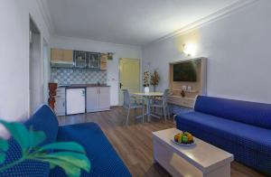 a living room with a blue couch and a kitchen at Angora Apart Hotel in Alanya