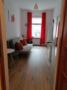 a living room with red curtains and a couch at Hostel Tulip - Pokój 1 ze wspólną łazienką i kuchnią in Szczecin