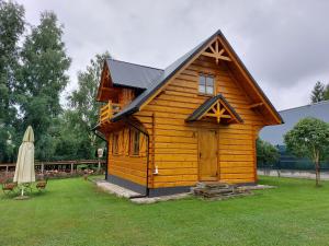 a small wooden cabin in a yard with a umbrella at KANADYJKA domki drewniane in Niedzica
