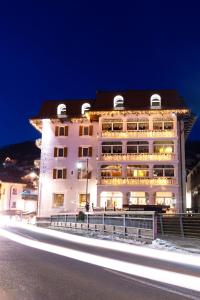 een groot wit gebouw 's nachts met verlichting bij Hotel Faloria in Moena