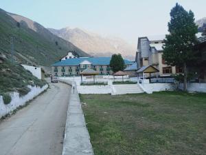 a building with a road in front of a field at Troutland Hotel Naran in Naran