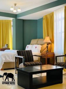 姆萬紮的住宿－LEYSHOF HOTEL，客厅配有床、沙发和桌子