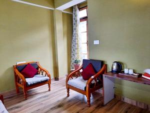 a room with two chairs and a table and a window at Kalimpong Sunrise-Inn Homestay in Kalimpong
