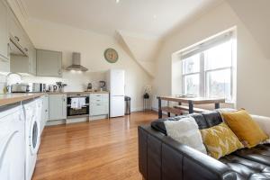uma cozinha e sala de estar com um sofá e uma mesa em Skye Sands - Central Apartment near The Old Course em St. Andrews