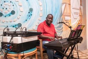 un hombre sentado en una silla con un teclado y un micrófono en Leopard Beach Resort and Spa, en Diani Beach