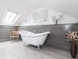 a white bath tub in a bathroom with a window at Rock Pool House in Helston +31 photos