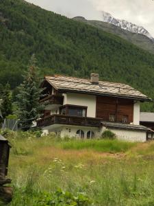 a house in the middle of a field with a mountain at Stilvolle grosszügige 7.5 Zi Maisonette Wohnung 10 Pers in Saas-Fee