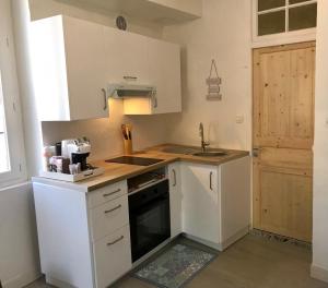 eine kleine Küche mit weißen Schränken und einem Waschbecken in der Unterkunft Appartement 3 pièces lumineux au cœur du village in Saint-Martin-Vésubie