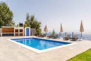a swimming pool with chairs and umbrellas on a house at SUNNYSIDE VILLA in Calheta
