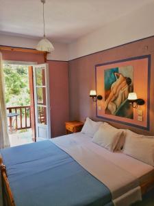 a bedroom with a bed with a painting on the wall at Limnonari Beach Rooms in Skopelos Town