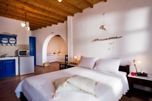 a bedroom with a large white bed and a kitchen at Arhitektoniki Studios in Astypalaia Town