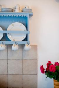 a shelf with plates and bowls and a vase with roses at Arhitektoniki Studios in Astypalaia Town