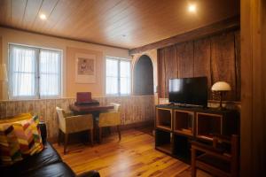 a living room with a couch and a television and a table at Casa da Praça Velha Guest House in Braga