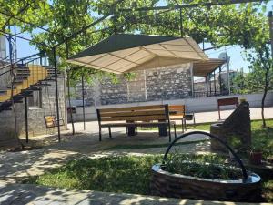 un banco del parque con una sombrilla grande y una cesta en Guest House Fazisi, en Kutaisi