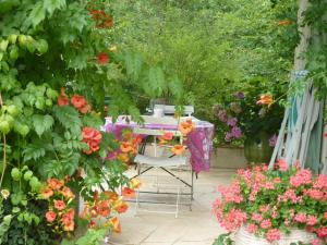 einen Tisch und Stühle in einem Garten mit Blumen in der Unterkunft L'orée du bois in Luzech