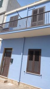 a blue building with a balcony and two windows at Appartamento U scrusciu ro mari in Marzamemi