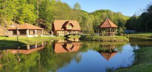 einen Fluss mit zwei Cottages und einer Brücke in der Unterkunft Imanje Izgubljena Dolina in Lepoglava