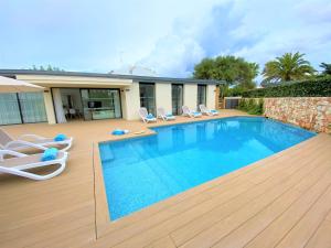 una piscina con sedie e una casa di Villa LUCIA a Cala en Blanes