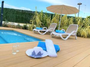 a group of chairs and umbrellas next to a pool at Villa LUCIA in Cala en Blanes