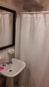 a bathroom with a white shower curtain and a sink at HOTEL KAPAC in Mendoza