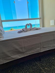 uma cama com dois cisnes em frente a uma janela em Suites Jangadeiro Maragogi 1 RUA JANGADEIROS 215 em Maragogi