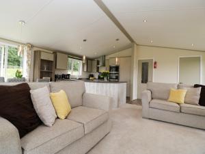 a living room with two couches and a kitchen at Hill View, Lilac Lodge in Wareham