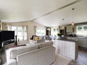 a living room with two couches and a kitchen at Hill View, Lilac Lodge in Wareham