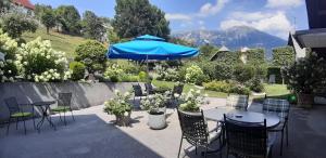 eine Terrasse mit Tischen, Stühlen und einem blauen Sonnenschirm in der Unterkunft Apartments Vesna in Bled