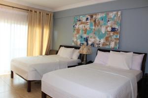 Bojo Beach Resort في Botianaw: سريرين في غرفة نوم مع لوحة على الحائط