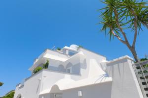 a white building with a palm tree in the foreground at Ischia Mavilan Luxury Apartments in Ischia