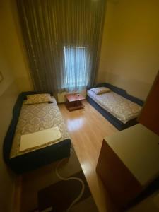 Habitación pequeña con 2 camas y ventana en Hotel Santos, en Skopje