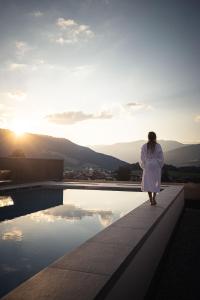 une femme debout sur le bord d'un bâtiment et regardant le coucher du soleil dans l'établissement Alpinhotel Keil, à Valdaora