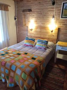 Un dormitorio con una cama con una colcha colorida. en Cabaña Los Espinillos de San Isidro en José de la Quintana