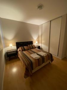 a bedroom with a bed with two tables and two lamps at Departamento Chivilcoy Abasto in Chivilcoy