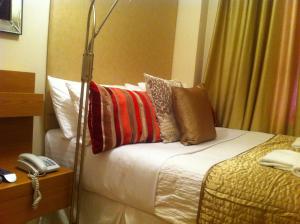 a hotel room with a bed with pillows and a phone at ABC Hyde Park Hotel in London