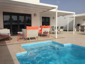 a swimming pool on a patio with chairs and a table at Casa Alice in Playa Blanca